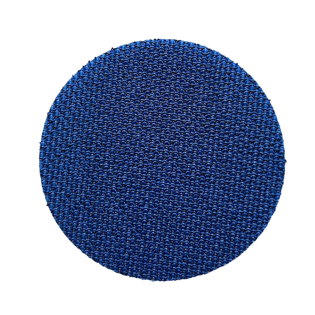 Klettauflage_60mm_selbstklebend_freigestellt Nahaufnahme einer runden blauen, strukturierten Fläche, die die untere Bildhälfte einnimmt und ein dichtes, sich wiederholendes, gewebt wirkendes Muster mit kleinen erhabenen Punkten und dezenten Glanzlichtern vor weißem Hintergrund zeigt.